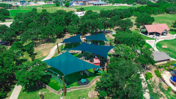 istock Aerial view modern playground with shade sail structure, artificial grass turf, kid friendly playing equipment, slides swings, lush greenery trees at suburban park in Flower Mound, Texas 2162516466