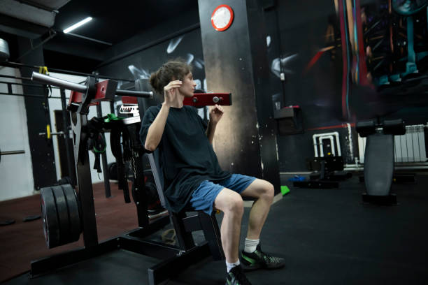 istock man in a black t-shirt performs a shoulder press exercise at a gym, lifting weights with his arms extended overhead 2162517966