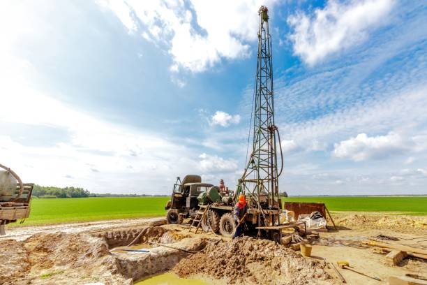 Worker drilling into the earth with his well drilling machine to extract water. Drilling equipment, drills well for water extraction