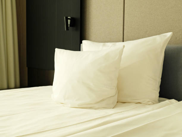 istock Close-up fragment of bedroom with empty bedside table, reading lamp and a USB socket in modern interior​ design home or hotel. Soft pillow and blanket, stylish comfortable furniture. 2162519872