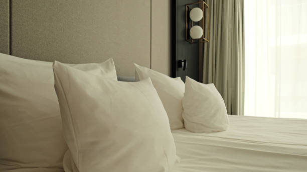 istock Close-up fragment of bedroom with empty bedside table, reading lamp and a USB socket in modern interior​ design home or hotel. Soft pillow and blanket, stylish comfortable furniture. 2162519888