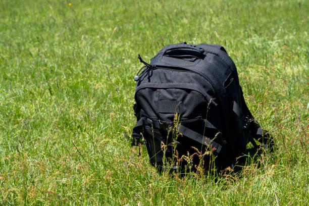 Black photographic backpack left on the grass-meadow.