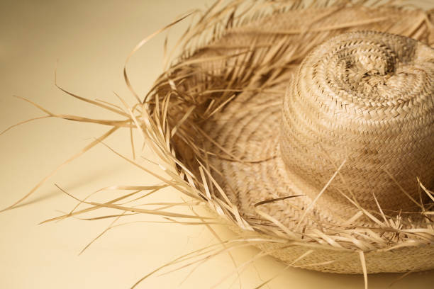 istock A large summer straw hat from which protruding straws on a sand-colored background 2162524837