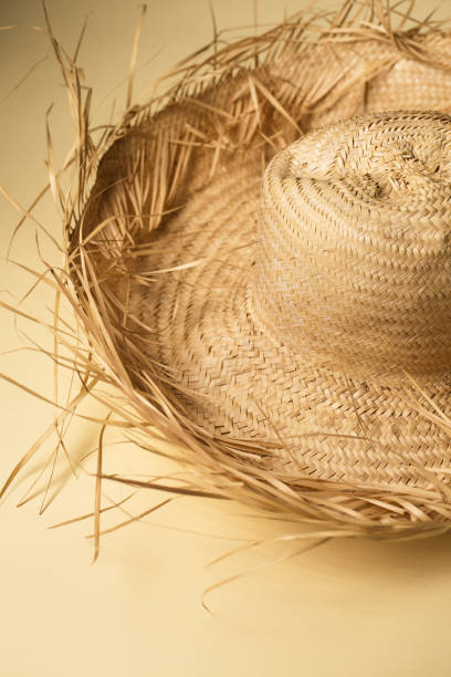 istock A large summer straw hat from which protruding straws on a sand-colored background 2162524840