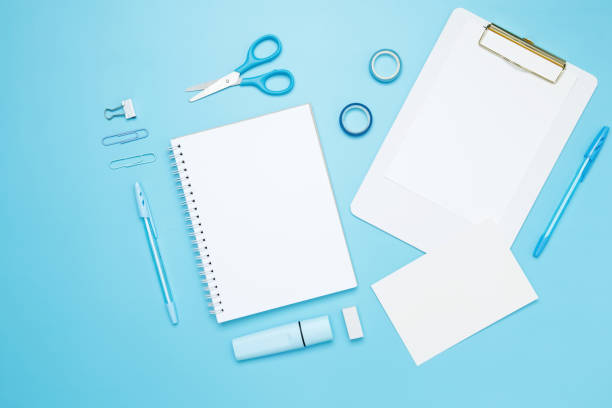 istock Creative flat lay mockup design of workspace. Top view composition with white notebook, to do list and stationery on blue background 2162526376