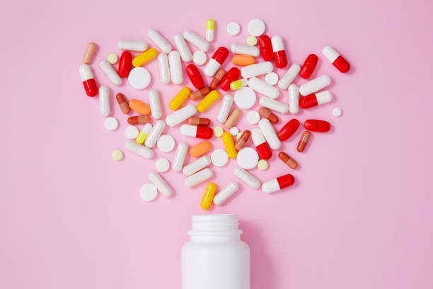 istock White bottle container with various colorful medication tablets and capsules on pink background. Concept of healthcare and medicine. Top view 2162527596