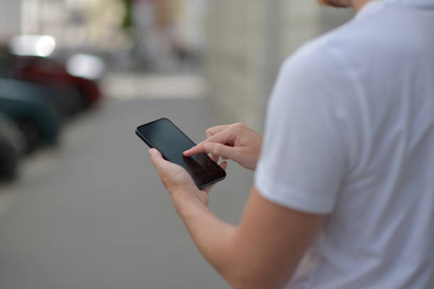 istock A man on the street using a smartphone. Mobile phone in hands close-up. 2162532391