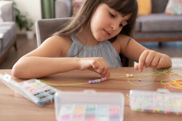 istock Little girl making bead bracelets 2162534799