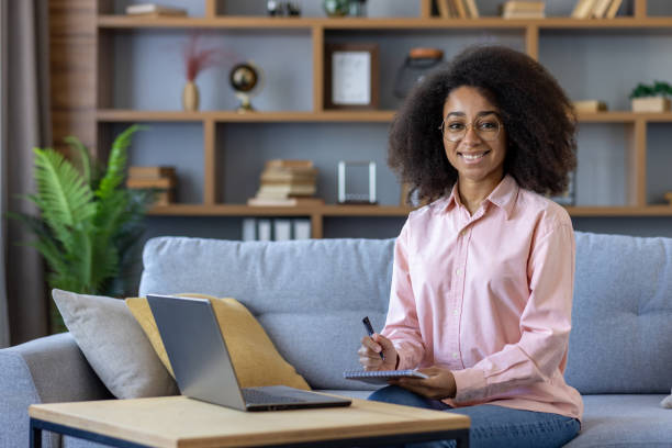 istock Smiling woman taking notes while working on laptop from home 2162535228