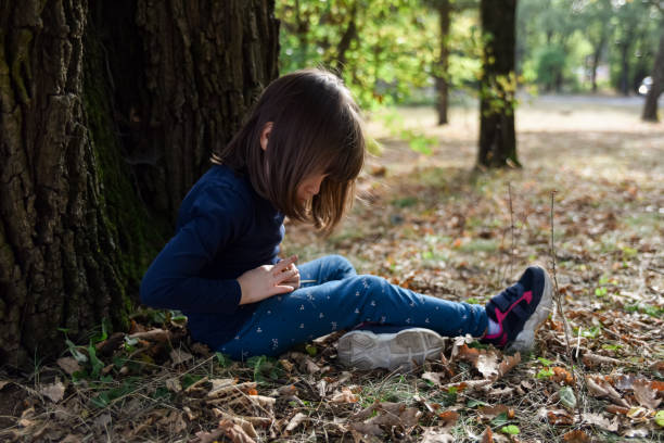 Girl sitting under oak tree in public park