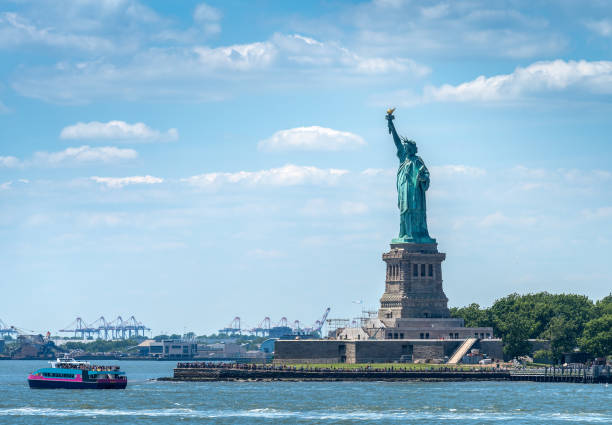 View of thousands of tourist around the world surrounding the Liberty Statue. The statue is an icon of freedom and the United States, later being seen as a symbol of welcome to immigrants arriving by sea.