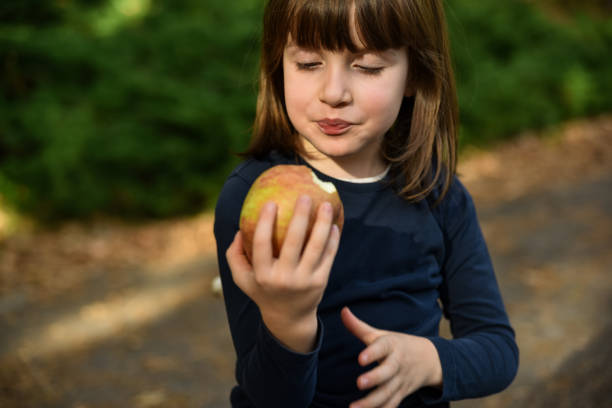 Cute little girl eating an apple in public park