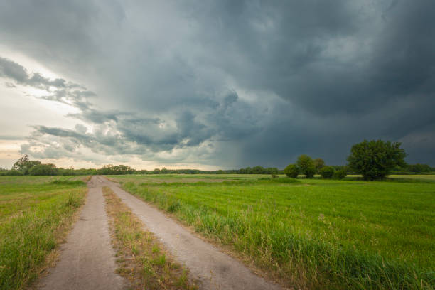 istock Rural road through green fields and storm clouds in the sky 2162548712