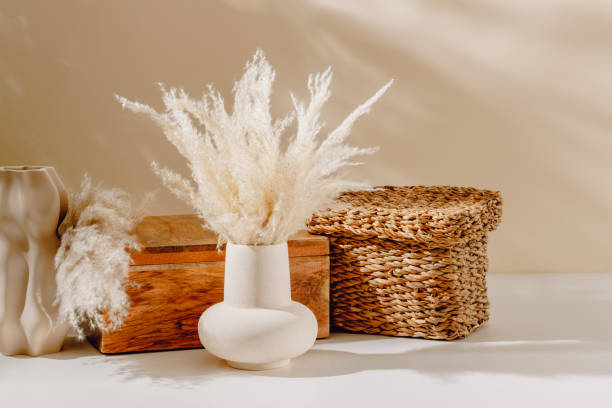 istock Ceramic vase with pampas grass, wooden box and wicker storage container with sunlight shadows 2162549660