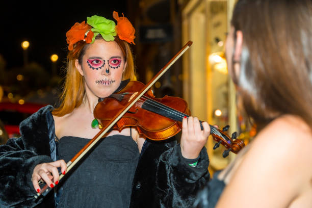 istock A girl is playing a violin with a skull painted on her face 2162549711