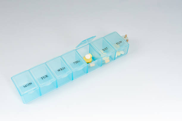 Pills organizer with supplements on yellow background  top view. Capsules in daily organizer. Weekly pillbox. Clear plastic pill container and medications. High quality photo