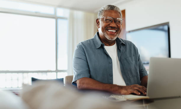 Confident senior man with eyeglasses using technology at home
