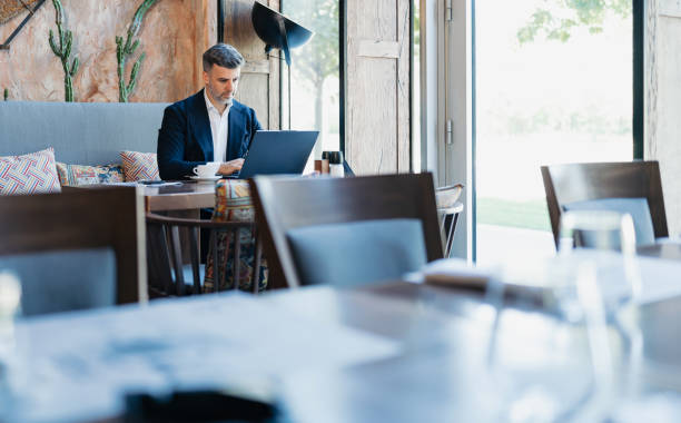 istock Man concentrating on laptop, holding coffee in cafe 2162553339