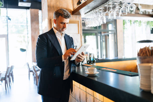 Businessman using tablet next to cup on cafe counter