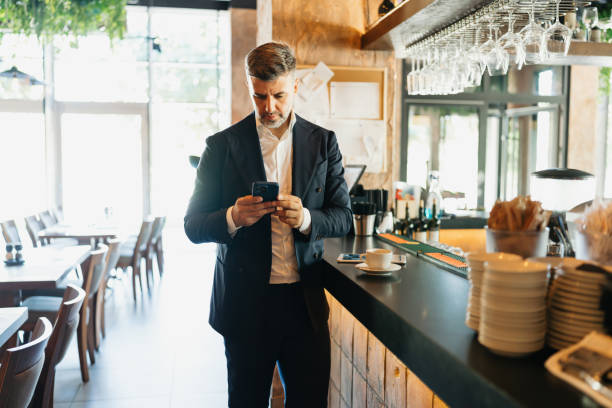 istock Businessman checking phone beside coffee on counter 2162553406