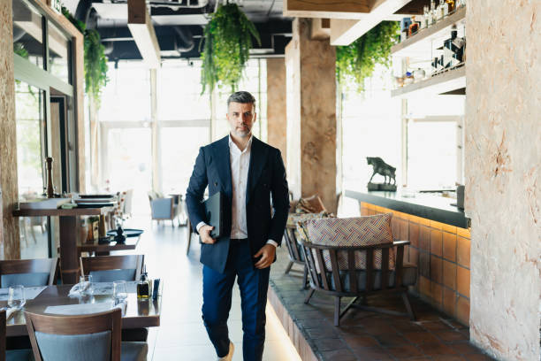 istock Stylish businessman walking in bright modern cafe 2162553446