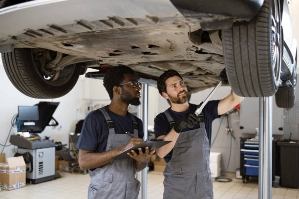 istock Two mechanics check vehicle chassis on lift in garage 2162554067