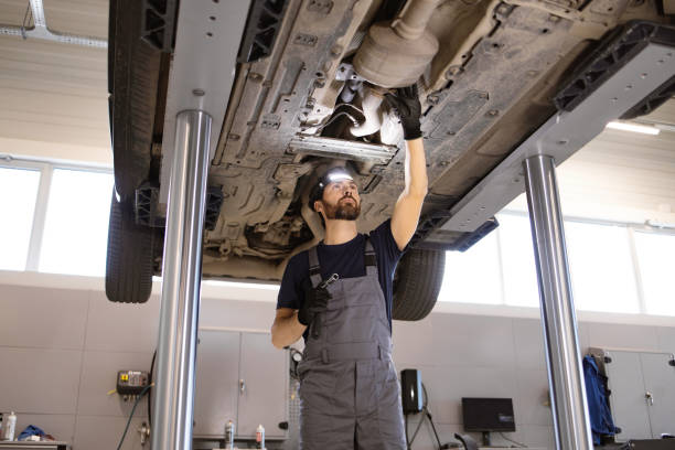 istock Auto mechanic inspecting car undercarriage on hydraulic lift 2162554104