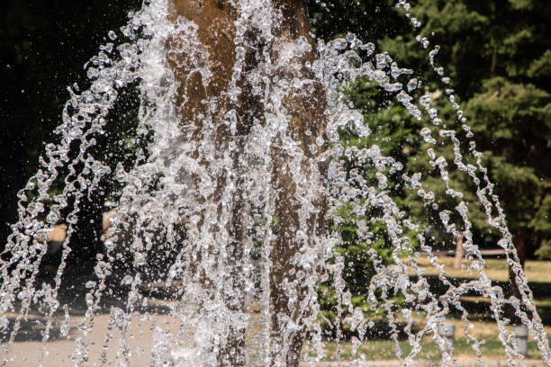 Sparkling water from fountain in city park on sunny summer day