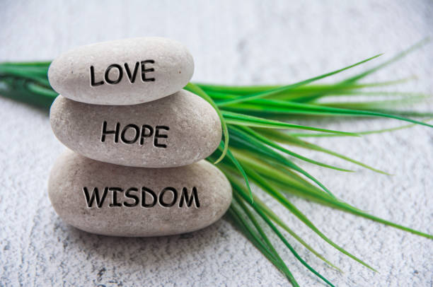 Love, hope and wisdom text engraved on zen stones.
