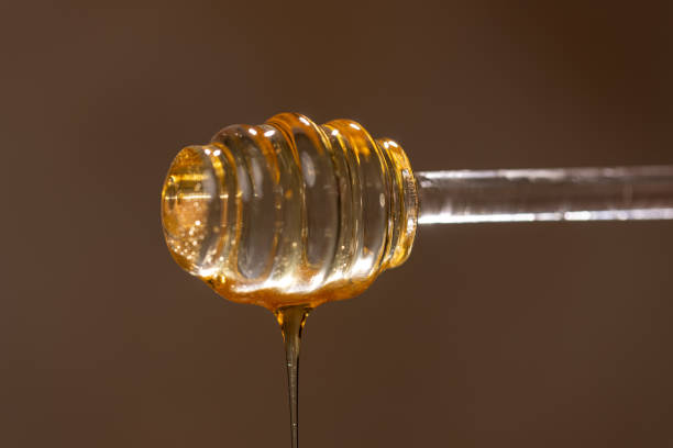 istock Fresh floral honey drips from a glass spoon, close-up 2162557050