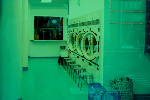 Woman wearing bandana checking inside open tumble dryer at laundromat during laundry routine