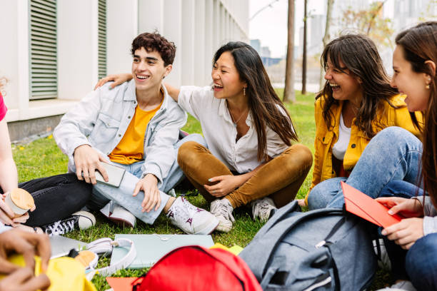 istock Student college group enjoying time together sitting at college campus park 2162562327