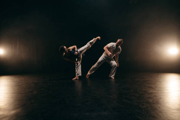 istock Couple of fighters training capoeira on black background 2162562430