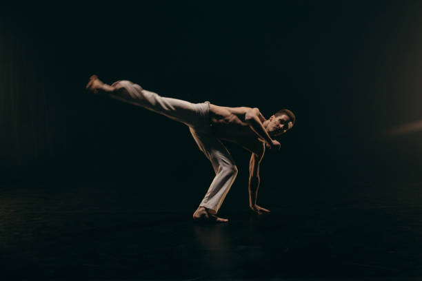 istock Male fighter training capoeira on black background 2162562505