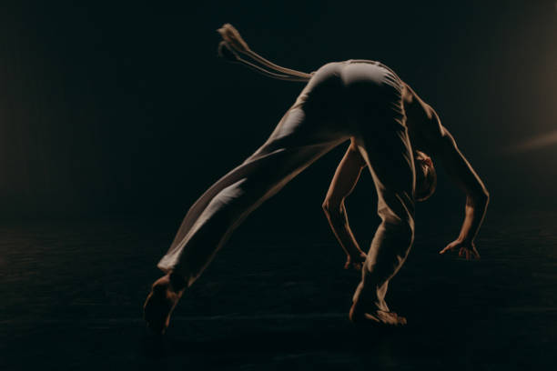 istock Male fighter training capoeira on black background 2162562542