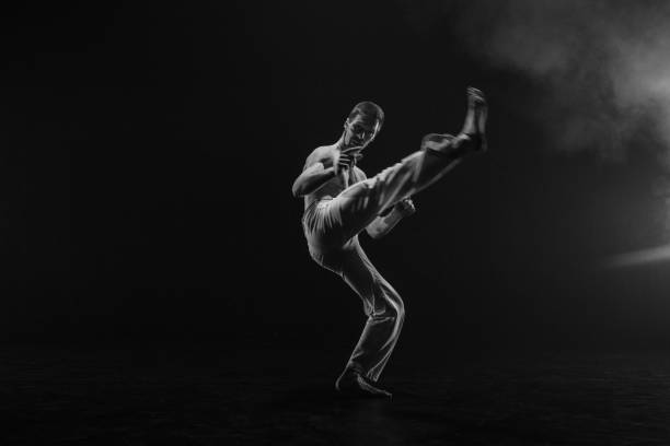 istock Male fighter training capoeira on black background 2162562580