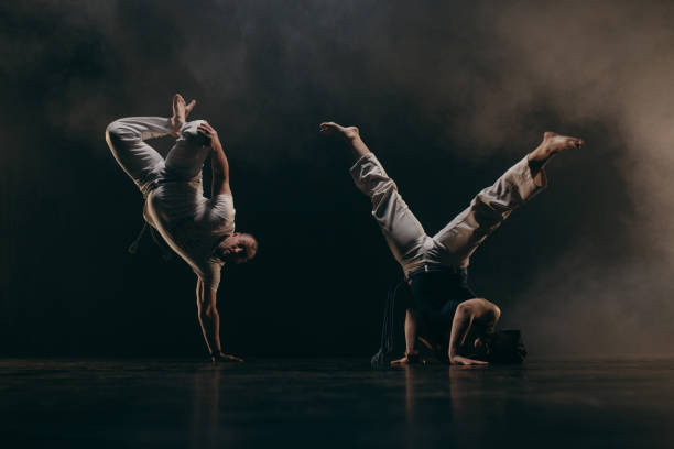 istock Couple of fighters training capoeira on black background 2162562641