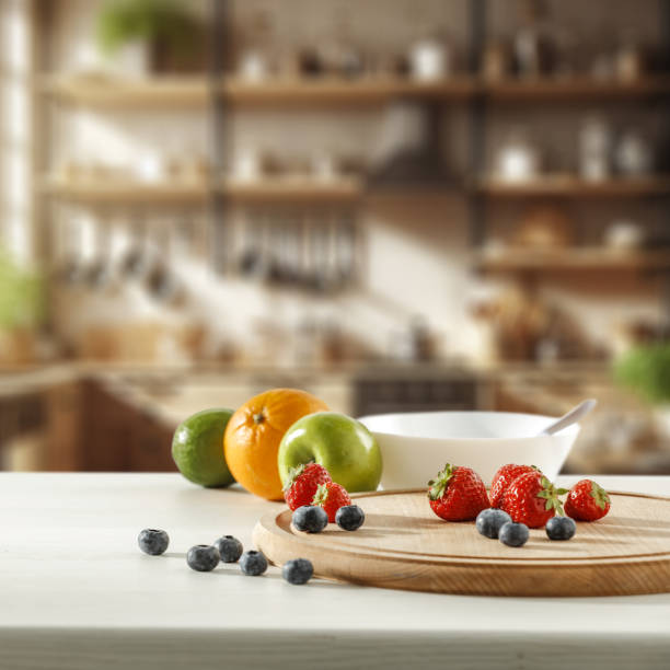 istock Blurred kitchen interior and fresh fruit on wooden cutting board on white countertop and space for food and drink and products and objects. Natural daily light coming through the window. 2162565116