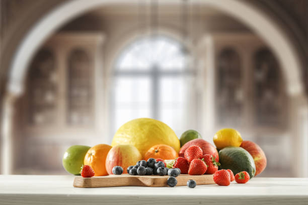 istock Blurred kitchen interior and fresh fruit on wooden cutting board on white countertop and space for food and drink and products and objects. Natural daily light coming through the window. 2162565132