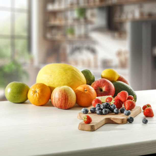 istock Blurred kitchen interior and fresh fruit on wooden cutting board on white countertop and space for food and drink and products and objects. Natural daily light coming through the window. 2162565157