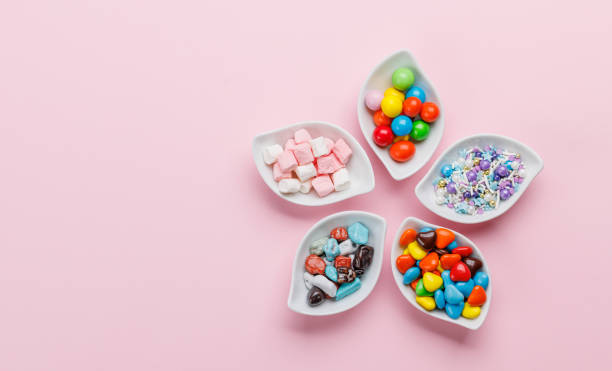Various colorful candies, lollipops. Flat lay over pink background with copy space