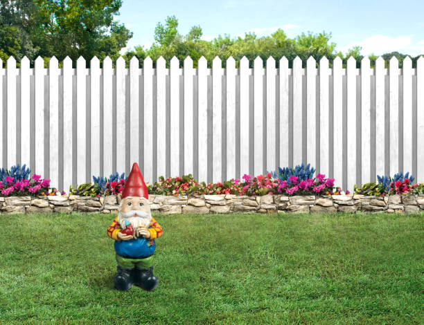Garden gnome in a backyard with white picket fence