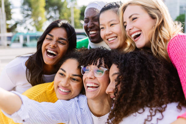Happy group of young diverse women laughing and smiling together at city street stock photo