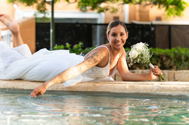 Bride lying by the pool and touching the water with her hand
