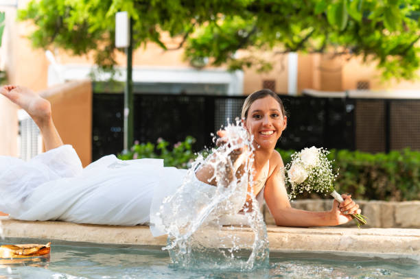 istock Bride lying by the fountain splashing water with her hand 2162573573