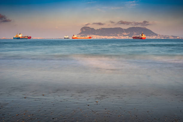 Serene evening at El Rinconcillo Beach, Algeciras, Spain. Long exposure captures cargo ships over Gibraltar bay at dusk.