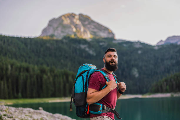 istock Man Hiking by Mountain Lake with Backpack 2162579467