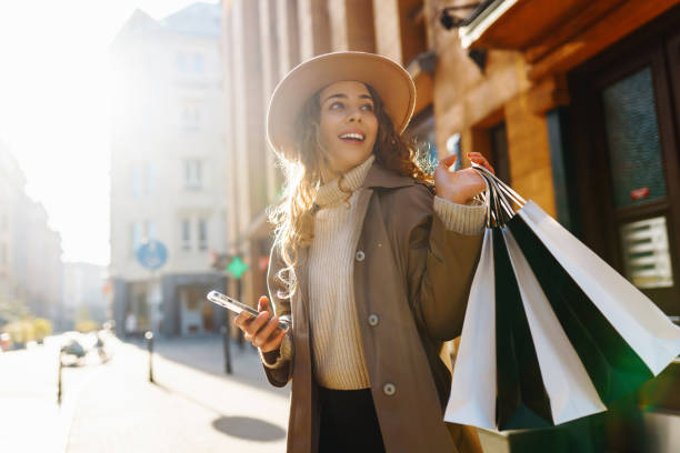 fall elegant woman carrying shopping bags walking city street. - koopwaar stockfoto's en -beelden