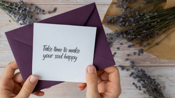 istock Female hands taking paper card note with text TAKE TIME TO MAKE YOUR SOUL HAPPY from violet envelope. Lavender flower. Top view, flat lay. Concept of mental spiritual health self care wellbeing 2162583111