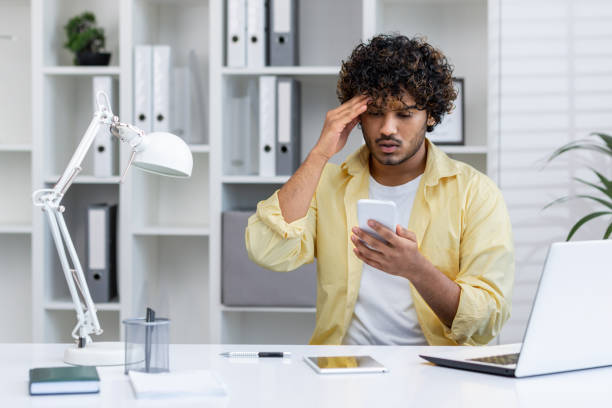istock Stressed man looking at smartphone in office setting, dealing with business issue 2162586926
